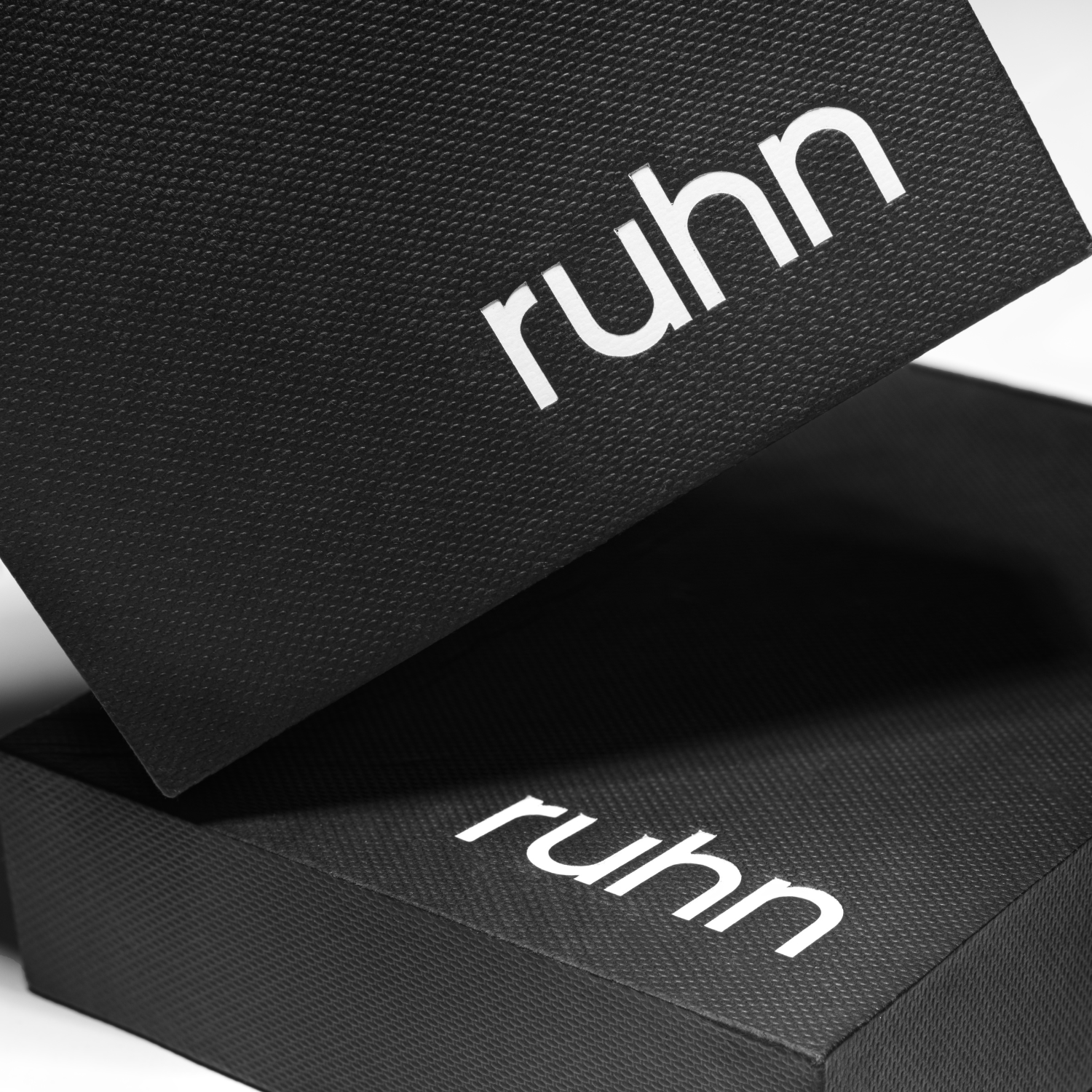 Close-up of textured black ruhn packaging box with white logo
