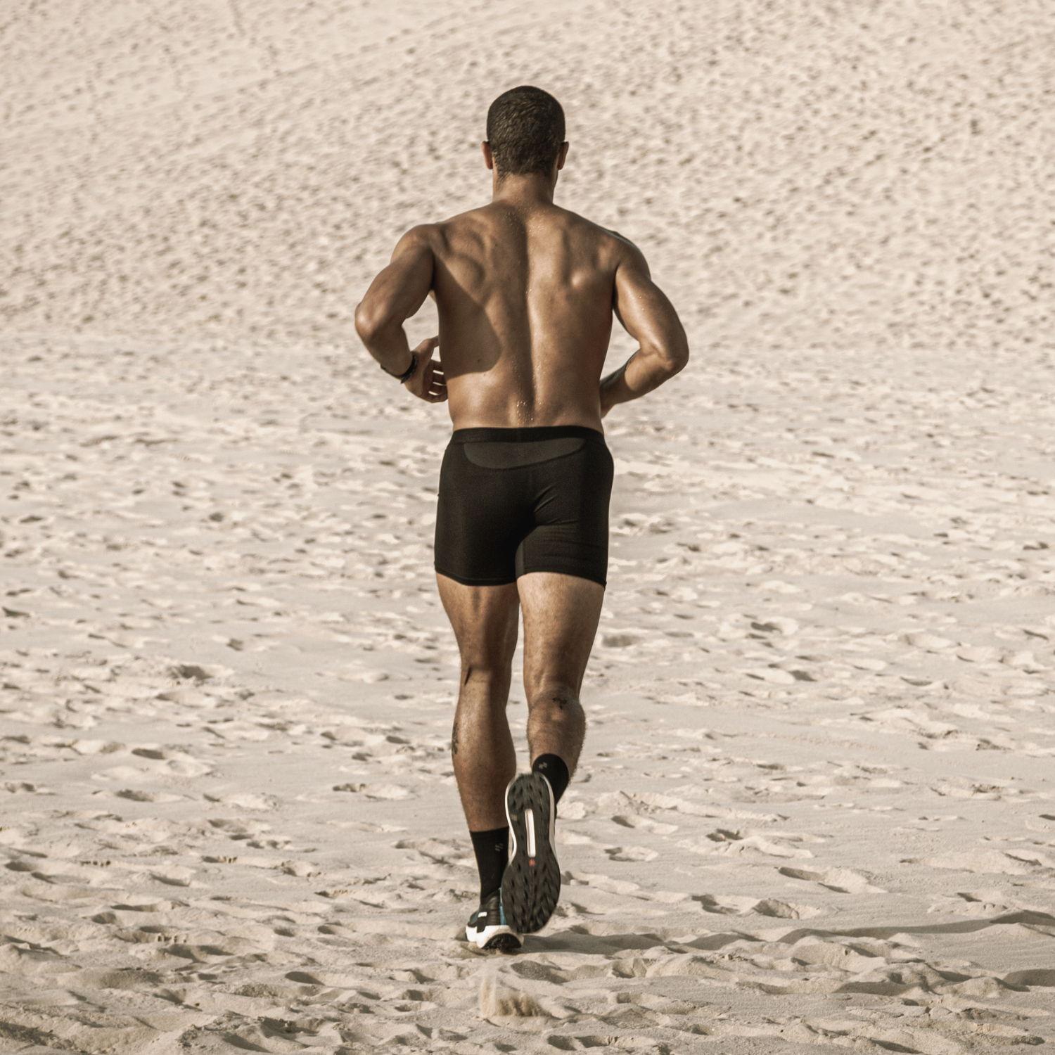 Man running on sand wearing ruhn performance underwear in activated black